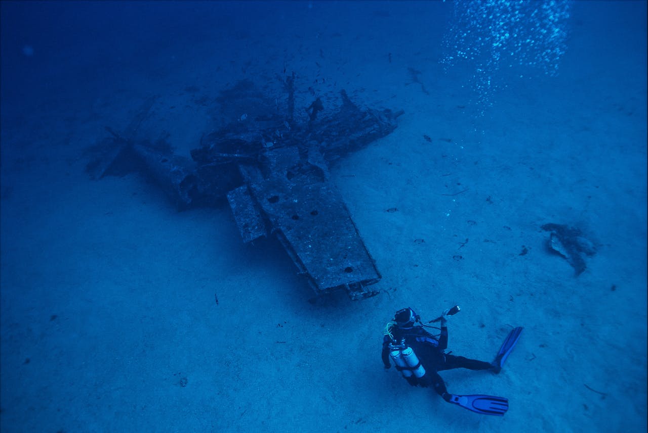 A scuba diver explores a submerged shipwreck deep underwater, capturing adventure and exploration.