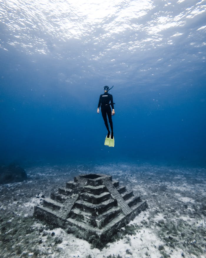 A diver explores an underwater pyramid structure in Cozumel, Mexicos clear blue waters.